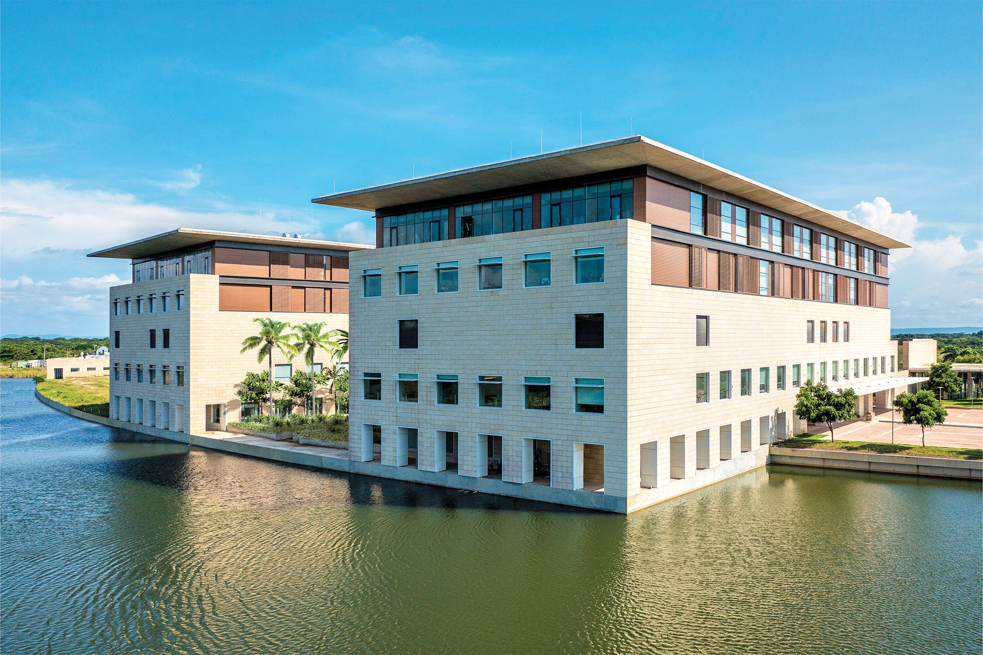 An exterior photograph of Serena del Mar Hospital in Cartagena, Colombia designed by Moshe Safdie. limestone volumes are separated by gardens, the building is situated along a waterfront.