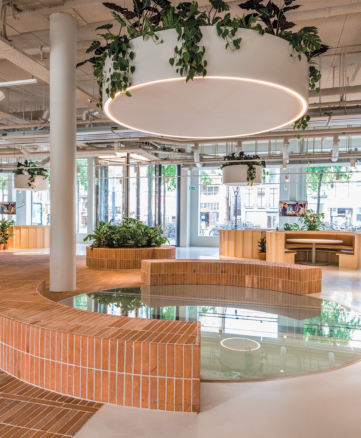 A circular light hanging on top of a waste brick made earthy seating in an open layout offie space with planets made in bricks as well.