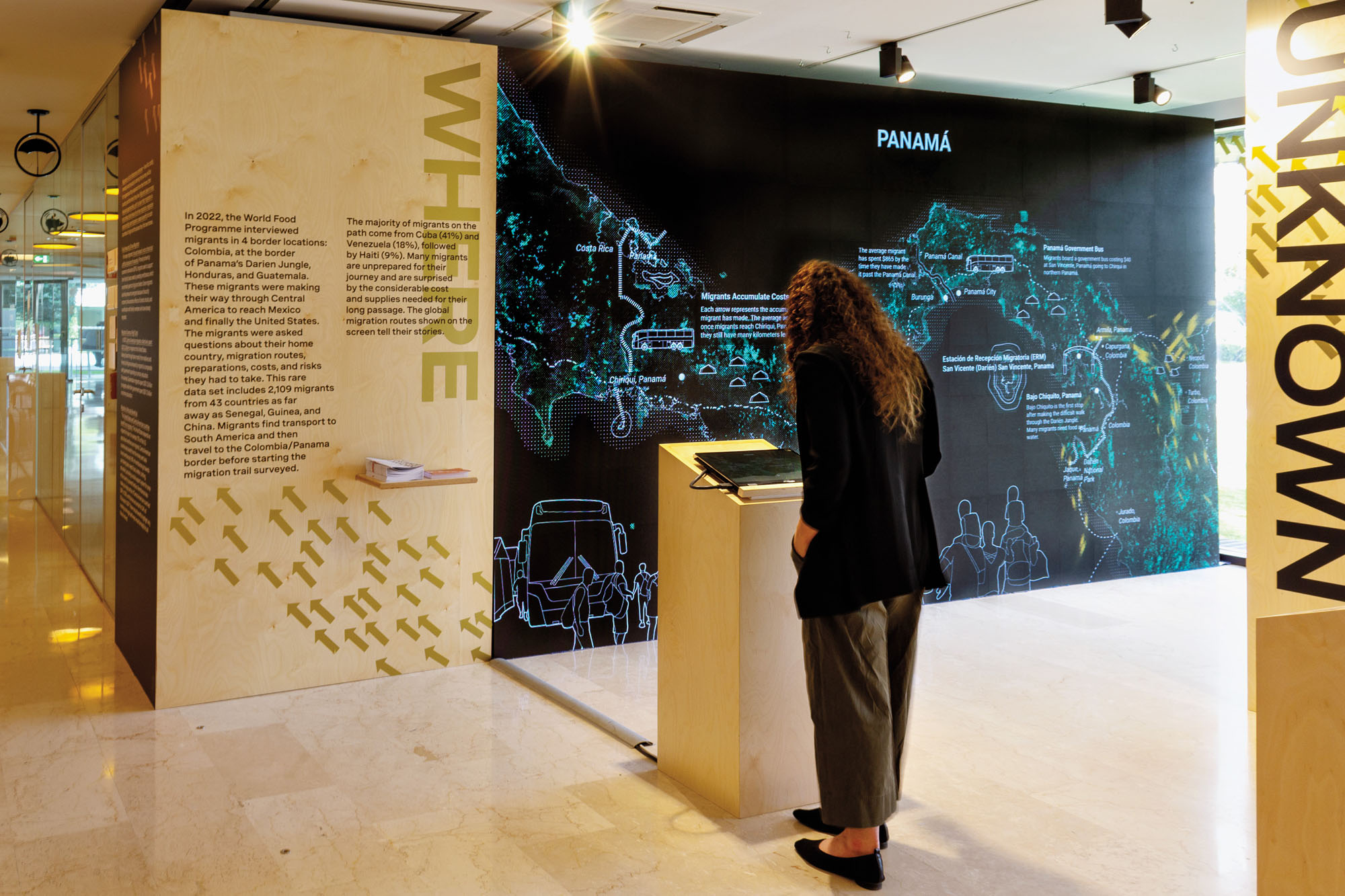 a person standing in an exhibition hall at MIT's Civic Data Design Lab in front of a map about migration data