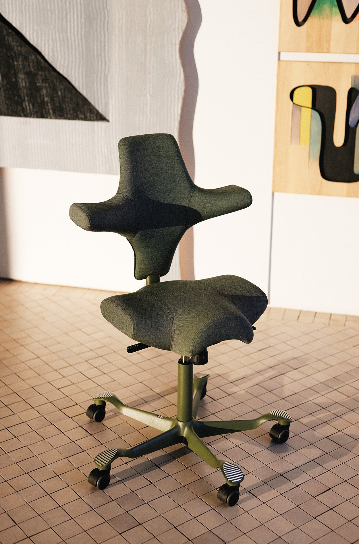 the HAG CApsico chair in moss green with its back shaped like a plus and the seat shaped like a 3 sided plus for giving enhanced support.
