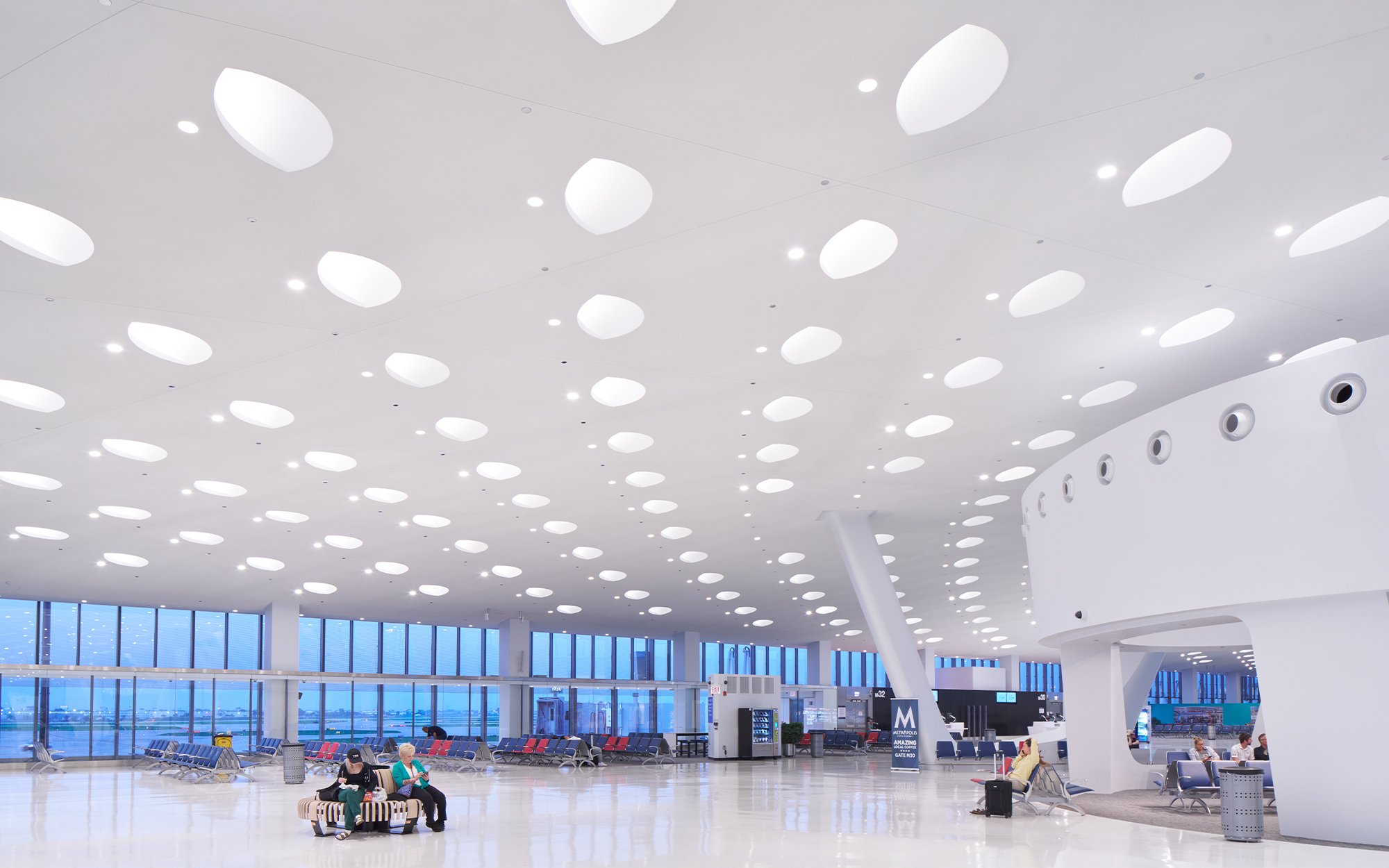 A airport with circular openings in the ceiling for skylight enhancing and making the space light.