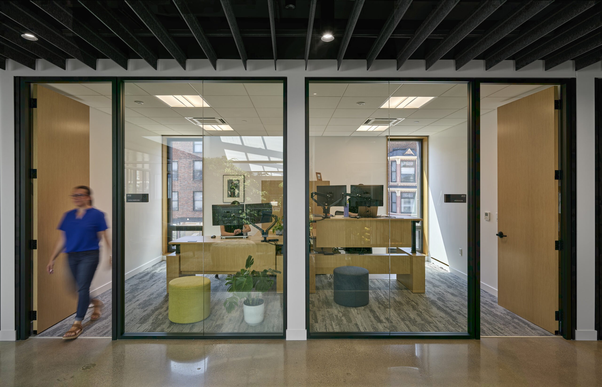 A person walking out of an office space with large clear glass all around.
